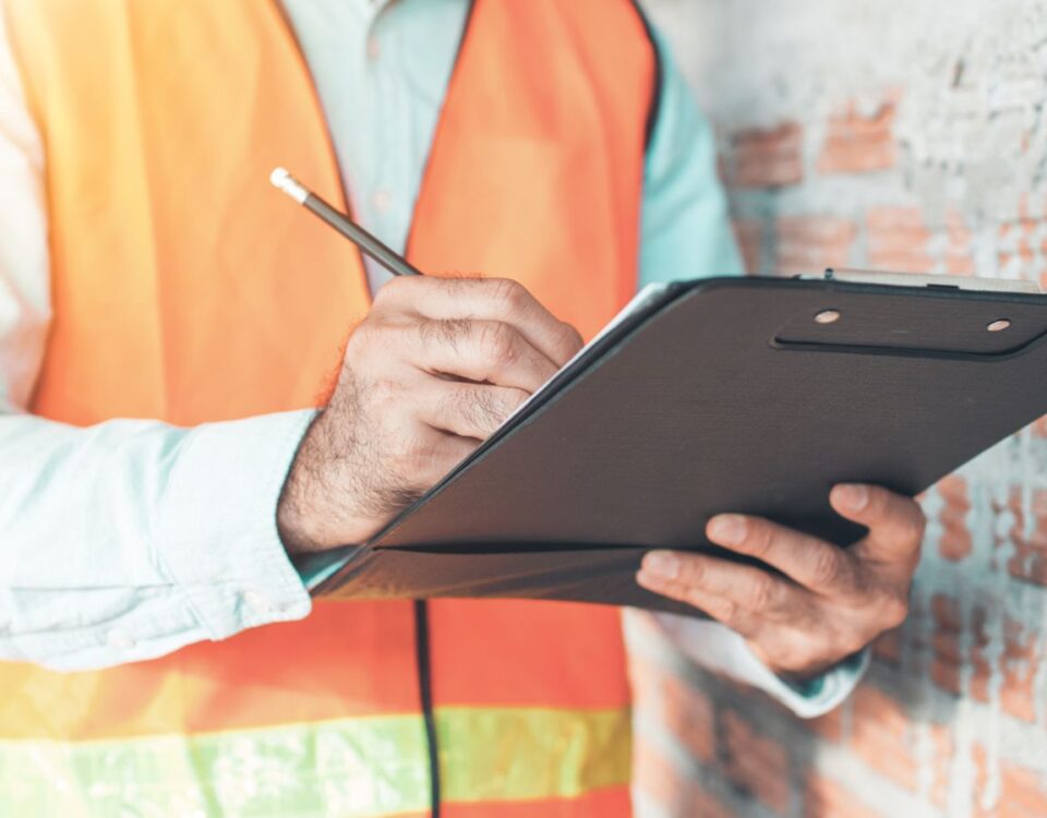 Fire safety advisor inspecting safety plan on clipboard at construction site.