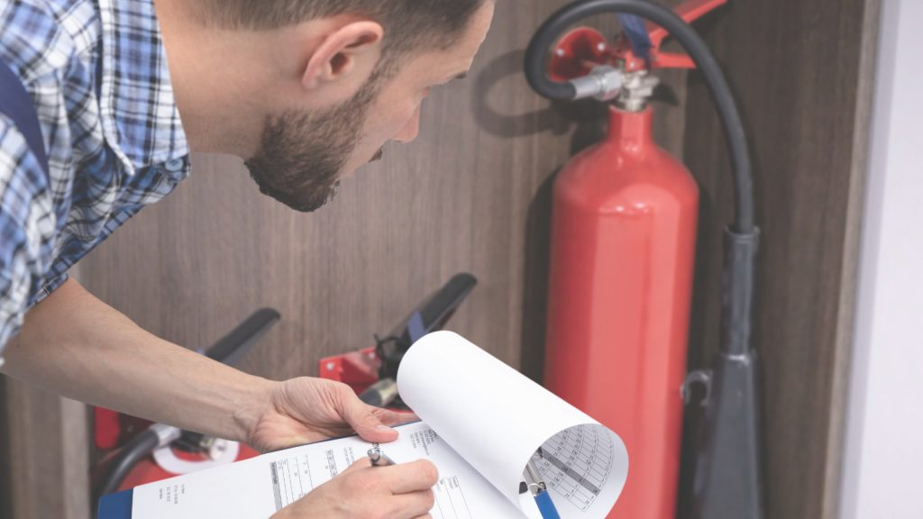 Fire safety advisor inspecting fire extinguisher and safety plan at workplace.