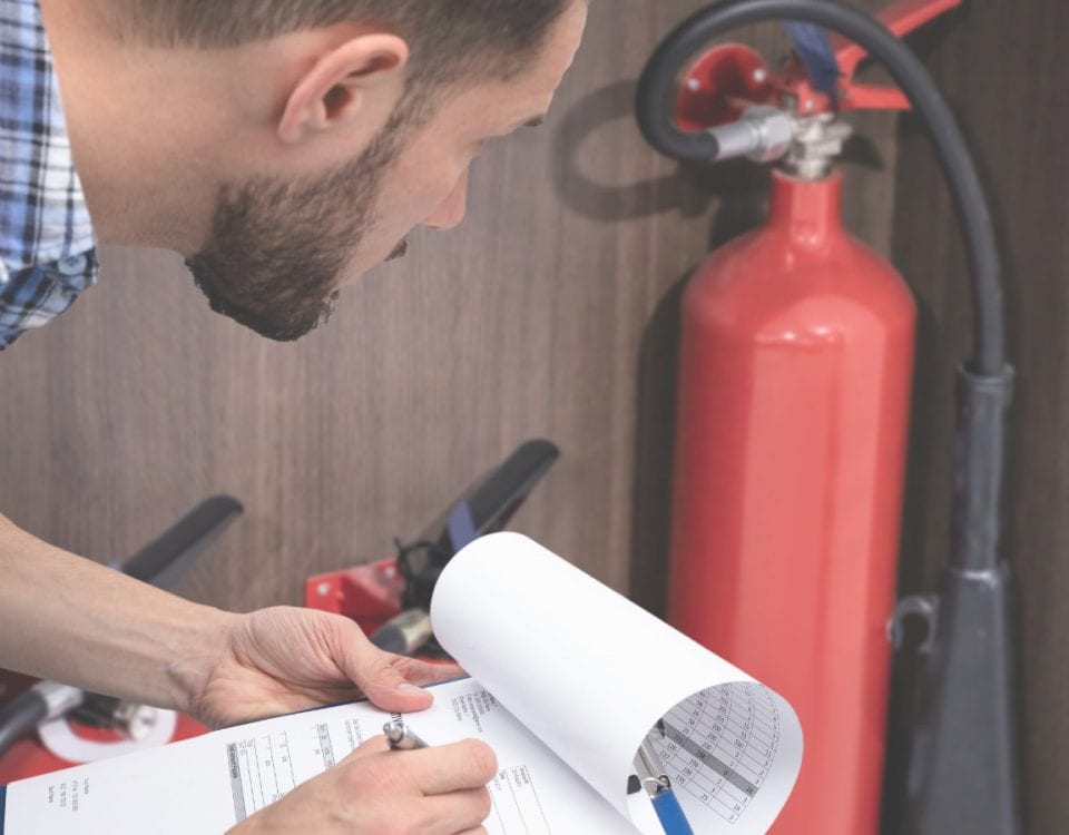 Fire safety advisor inspecting fire extinguisher and safety plan at workplace.